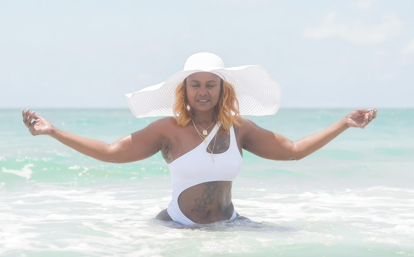 Woman praying with her hands outstretched at the beach.